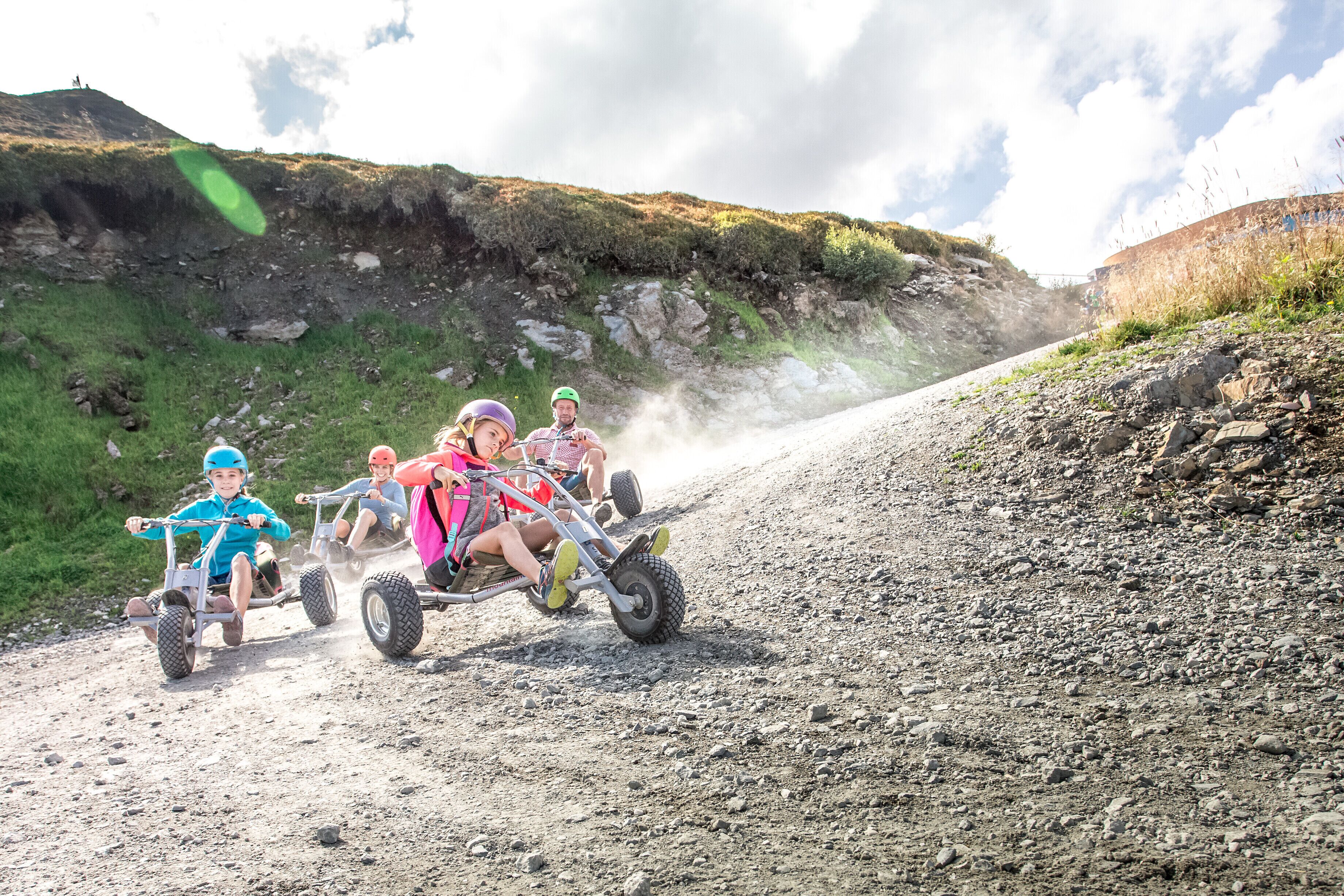 A group of people on a dirt road with a rocky hillside in the background.