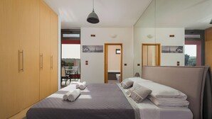 Un dormitorio con cama, armario de madera, espejo y vistas al exterior.