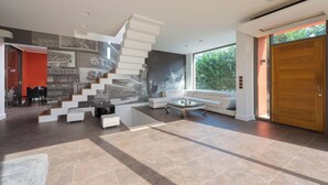 Un interior moderno con una escalera, una zona de comedor y un ventanal amplio.