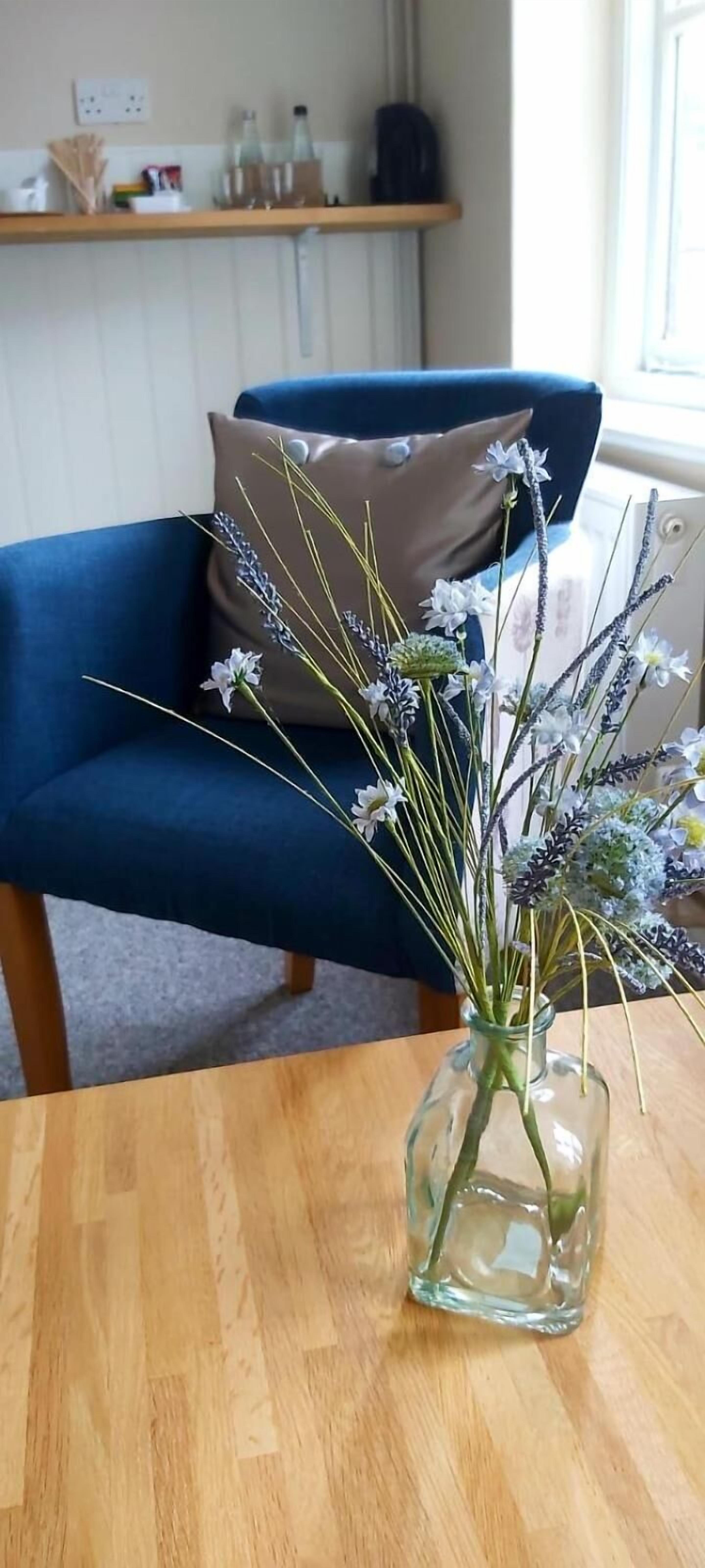 A clear view of a room with a wooden table, a blue chair, and a vase with flowers.