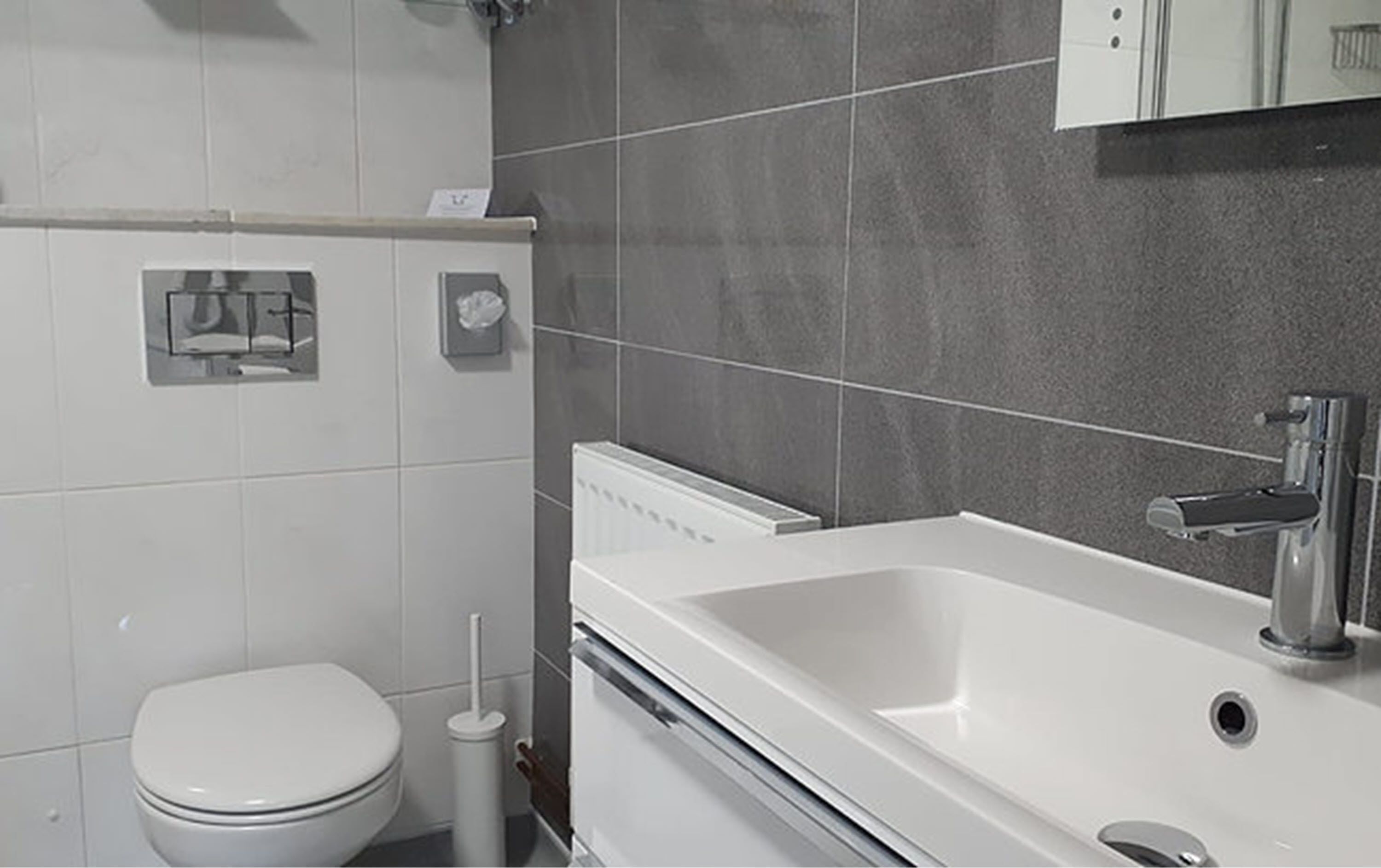 Ein modernes Badezimmer mit Toilette, Waschbecken und Spiegel.