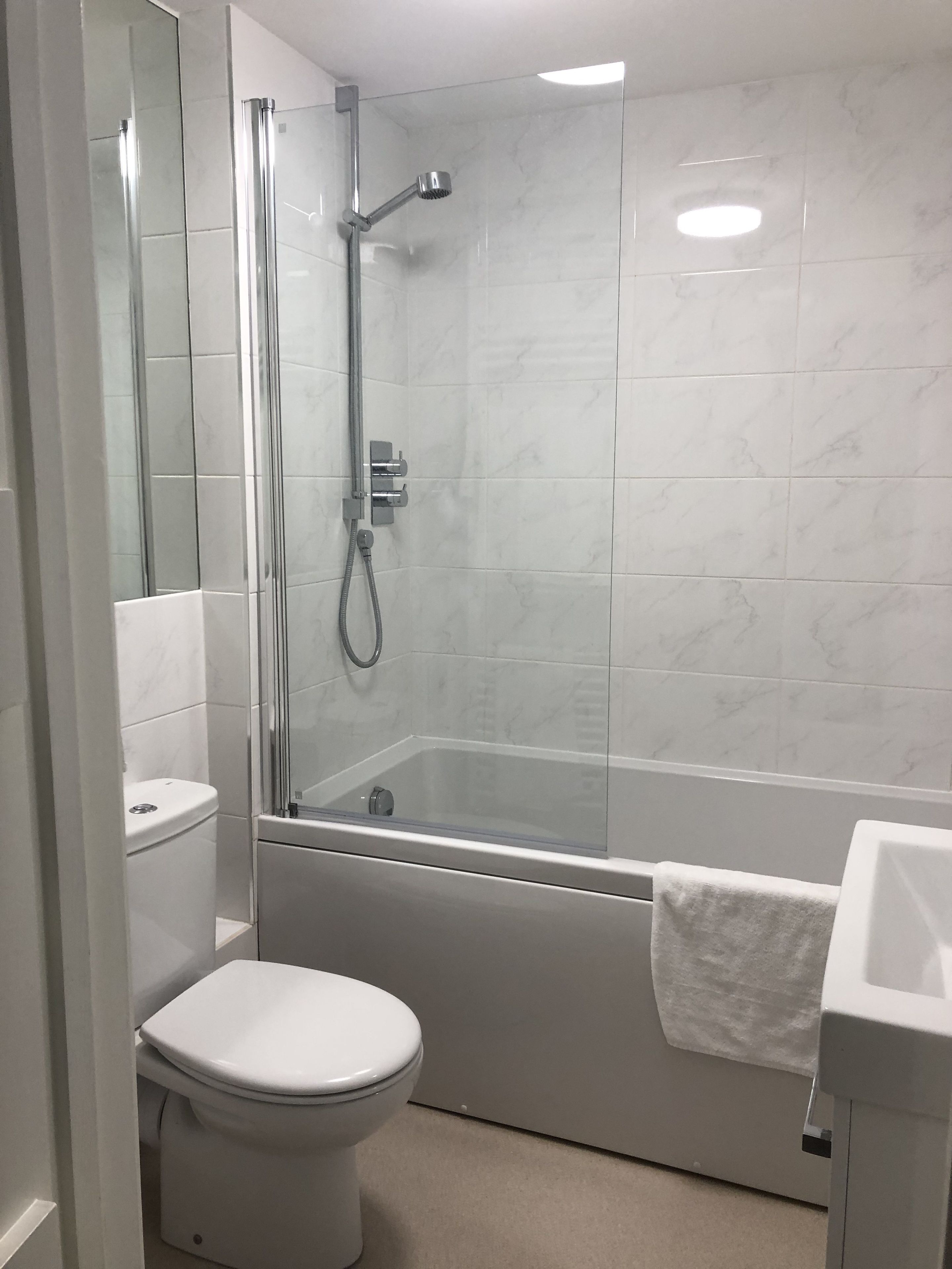 Un bagno moderno con doccia vetrata, un water bianco e un lavandino.