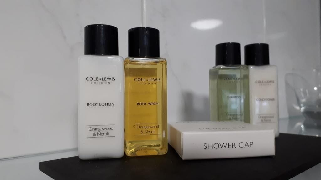 A set of toiletry bottles and a shower cap on a black surface.