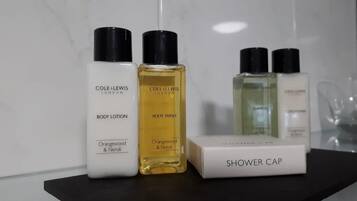A set of toiletry bottles and a shower cap on a black surface.