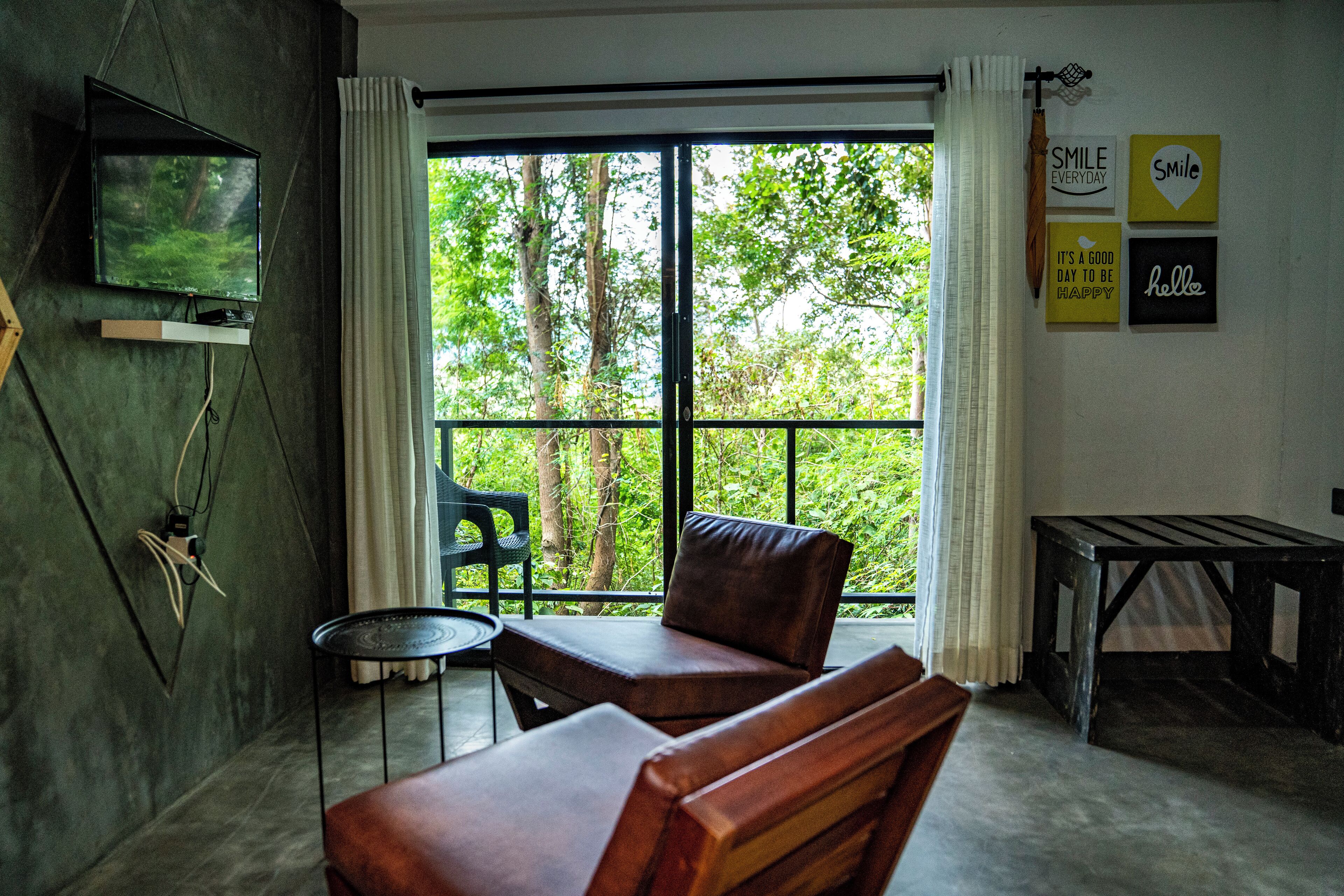 A room with a large window, a television, a sofa, a small table, and a bench.