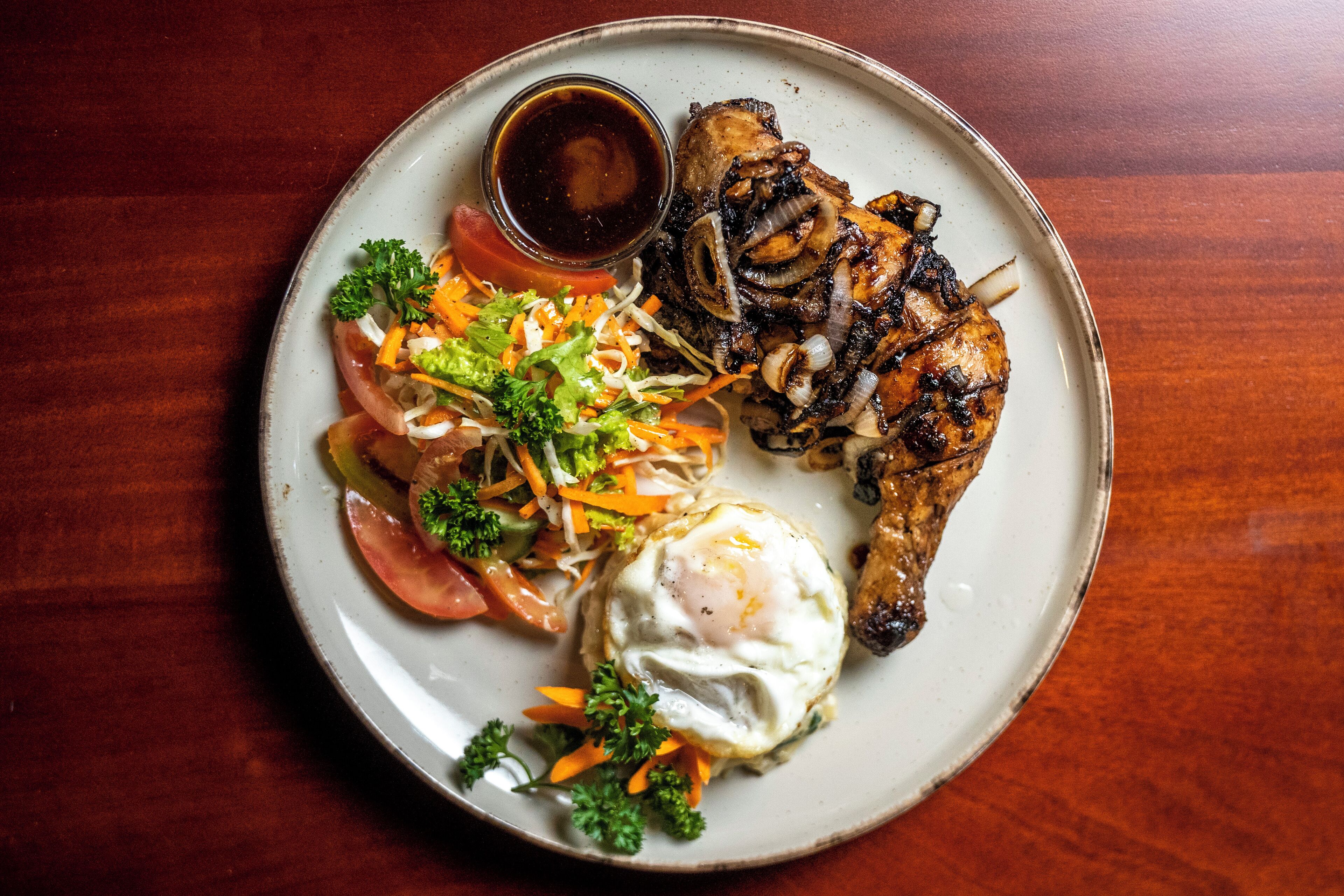 A plate with grilled chicken, a fried egg, and a side salad.