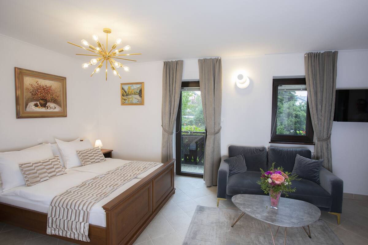 A bedroom with a bed, a sofa, a coffee table, and a painting on the wall.