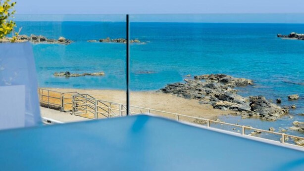 Blick auf einen Strand mit klarem, blauem Wasser und Felsformationen.