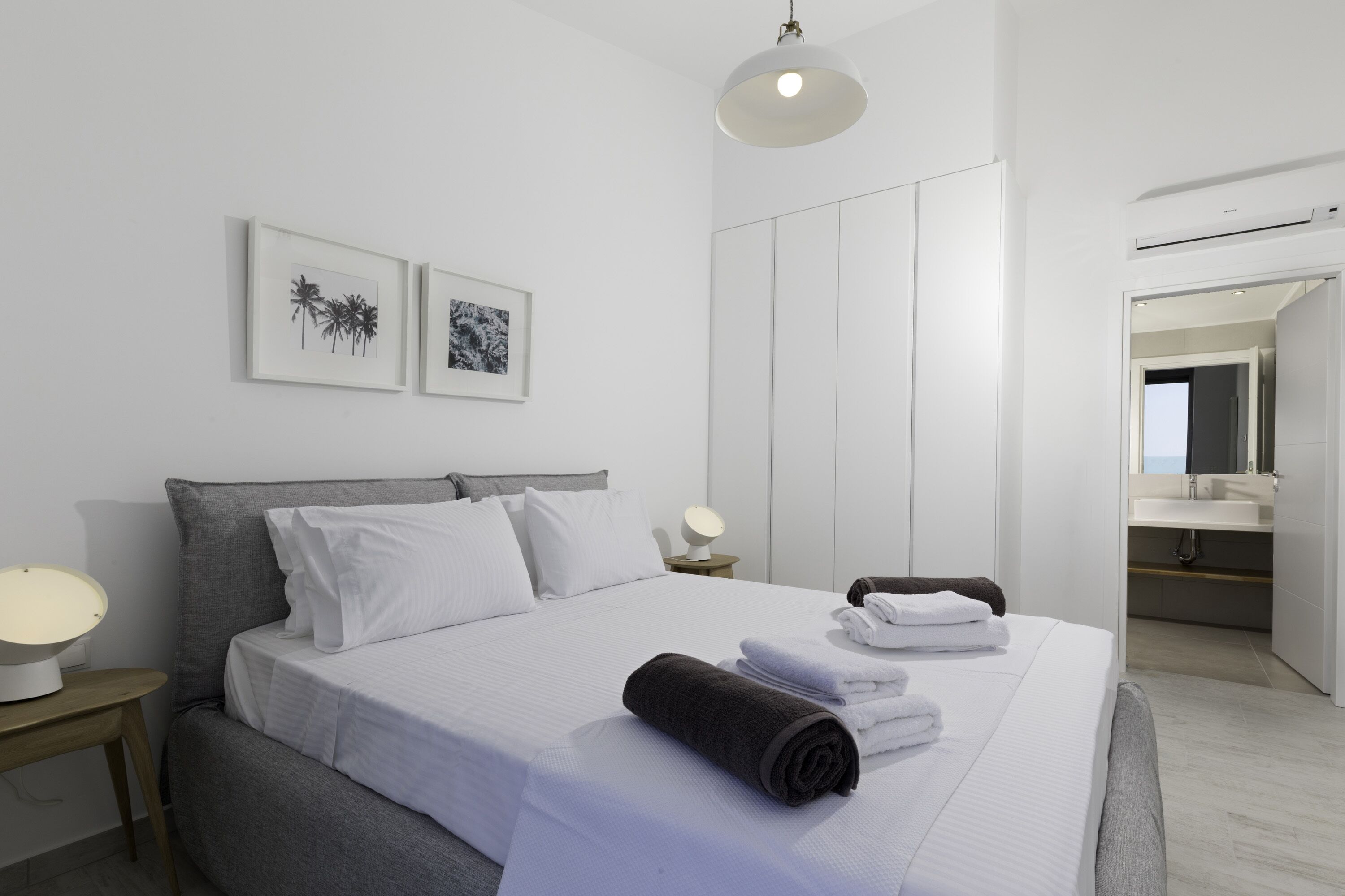 Una habitación de hotel moderna con una cama grande, una mesita de noche con lámpara y una obra de arte en la pared.