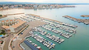A marina with numerous boats docked, a parking area, and buildings in the background. - Apartaments   Ponent first line of the sea (Escala, L')