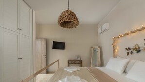 A bedroom with a bed, a TV, a mirror, and a wardrobe. - Villa Evelyn with Private Pool (Αρχάγγελος)