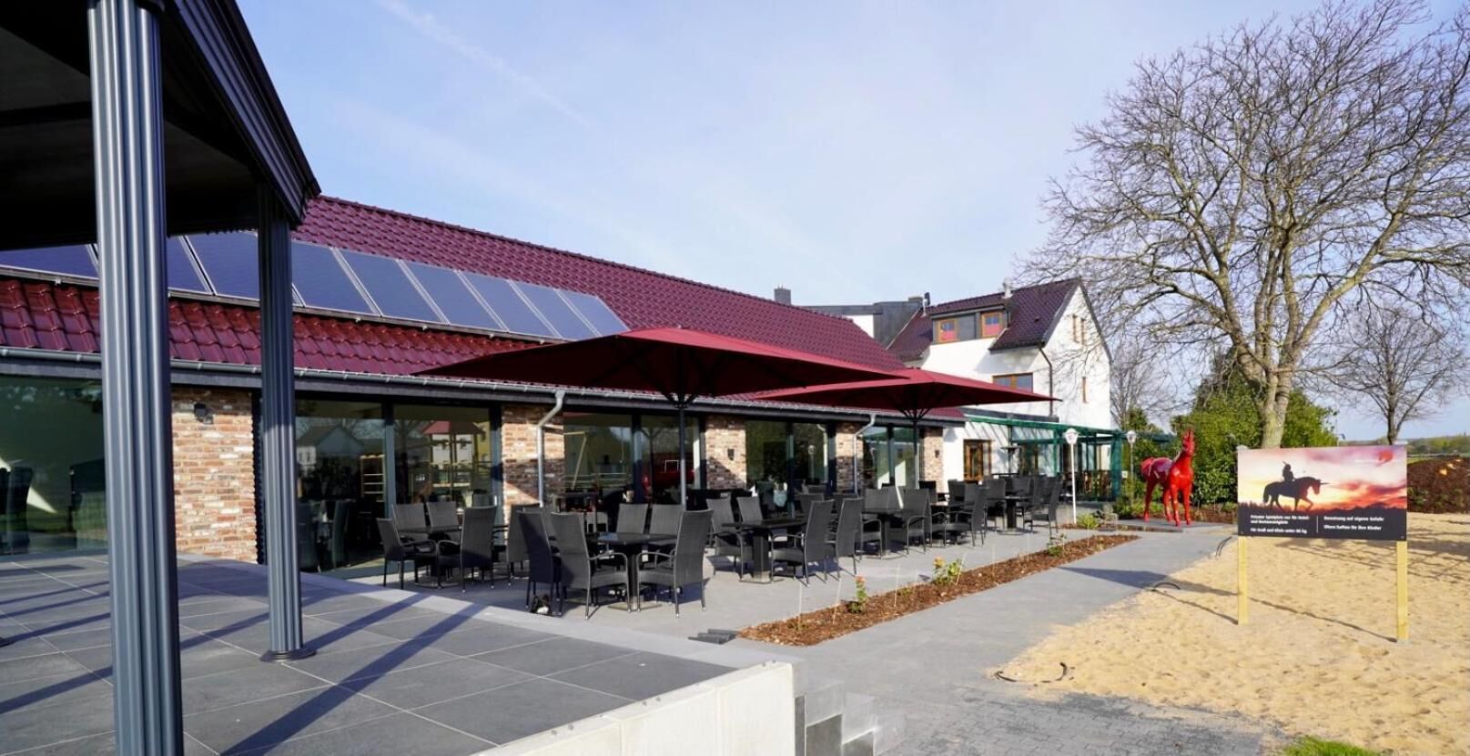 An outdoor seating area with tables and chairs, a covered patio, and a solar panel roof.