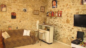 Una stanza accogliente con parete in pietra, un divano, un piccolo angolo bar e una televisione.