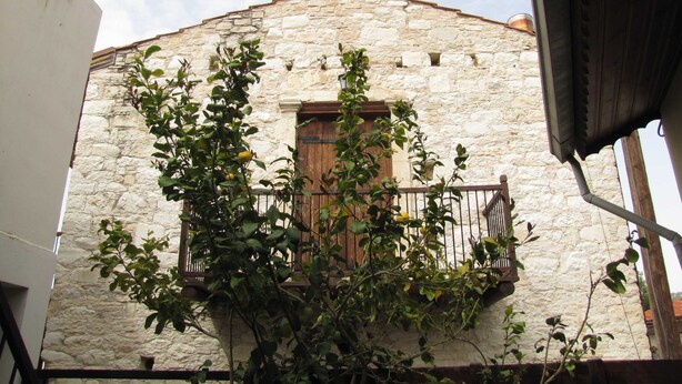 Un edificio in pietra con un balcone in legno e una finestra.