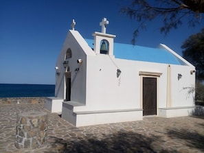 A small white church with a blue roof, located near a body of water.
