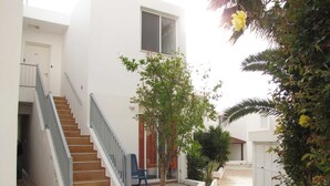 A residential building with a staircase, a small tree, and a concrete pathway. - Webooking Pegia Apartment (Pegeia)