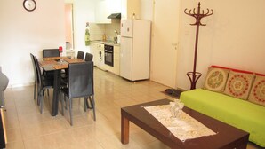 A compact living space with a dining area, kitchenette, and a green sofa. - Webooking Pegia Apartment (Pegeia)