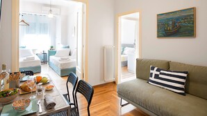 A modern living room with a sofa, a dining table set with plates and glasses, and a painting on the wall. - Attractive Flat near the Acropolis Museum - Athenian Homes, Athenian Homes (Athens)