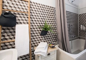 Een bad/douchecombinatie, een haardroger, handdoeken