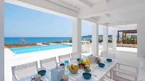 Comedor con vista a la piscina, mobiliario blanco y una mesa dispuesta para dos.
