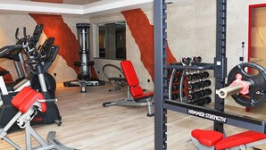 A gym with various exercise equipment, including treadmills, weight machines, and a squat rack with weights. - Hotel Rotes Einhorn (Dueren)