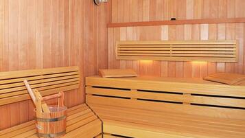 Una sauna de madera con bancos y un cubo de toallas.