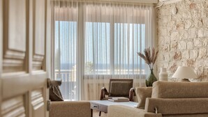 A living room with a view of the sea, a stone wall, and a sofa. - Ananta Blue Four Bedroom Apartment with full Sea View (Ξηροκάστελλο)