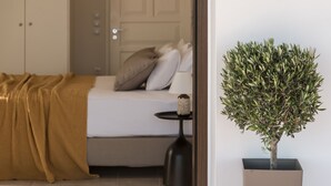 A bedroom with a bed, pillows, a bedside table, a lamp, a potted plant, and a wardrobe. - Ananta Blue Four Bedroom Apartment with full Sea View (Ξηροκάστελλο)