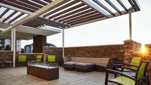 An outdoor patio area with a stone wall, wooden pergola, and seating arrangements including a sofa and chairs. - SpringHill Suites by Marriott Springfield North (Springfield)