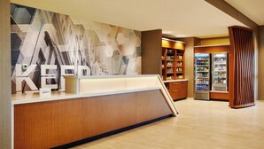 A hotel reception area with a modern design, including a reception desk, a wall with geometric patterns, and a minibar. - SpringHill Suites by Marriott Springfield North (Springfield)