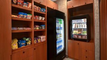 Zona de máquinas expendedoras con diferentes opciones de bocadillos y refrigerador para bebidas.