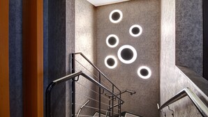 A modern staircase with a metal railing and circular light fixtures on the wall. - SpringHill Suites by Marriott New York Midtown Manhattan/Park Avenue (New York)