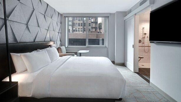 A modern hotel room with a large bed, a TV, a window with a city view, and a bathroom with a shower. - SpringHill Suites by Marriott New York Midtown Manhattan/Park Avenue (New York)