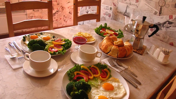 Une table à manger avec des assiettes remplies de nourriture, des couverts et une machine à café.