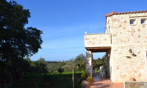 Un bâtiment en pierre doté d’un balcon, d’un jardin et offrant une vue sur la mer.