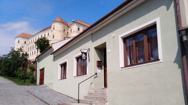 A building with a stone-paved entrance, a small staircase, and a flower planter. - Castle-Wall-Inn - Hostel (Mikulov)