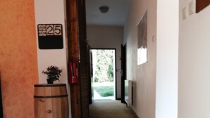 A hallway with a wooden barrel, a potted plant, and a sign indicating room number 25. - Castle-Wall-Inn - Hostel (Mikulov)