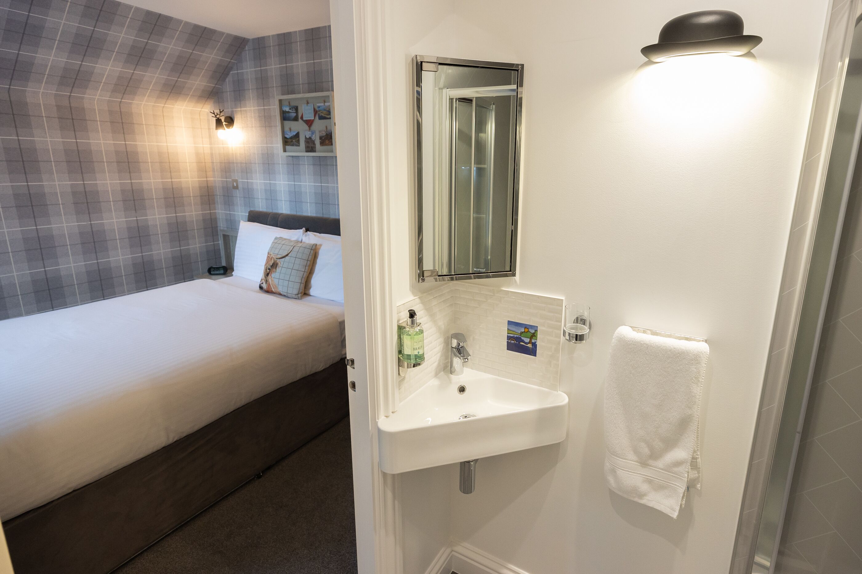 Une chambre à coucher avec un lit, un lavabo blanc, un miroir et une serviette accrochée au mur.