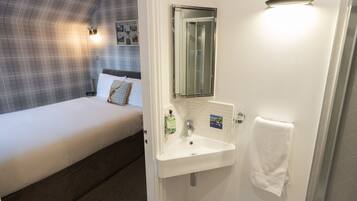 Une chambre à coucher avec un lit, un lavabo blanc, un miroir et une serviette accrochée au mur.