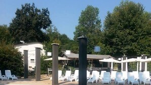 A swimming pool with lounge chairs and a covered area with columns. - Playa di Valverde - Campsite (Galliate)