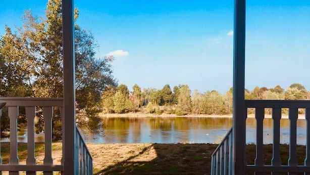 A wooden deck with a view of a calm lake surrounded by trees. - Playa di Valverde - Campsite (Galliate)