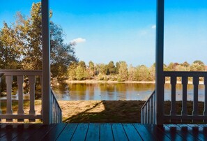 Una terraza de madera con vista a un lago tranquilo rodeado de árboles.