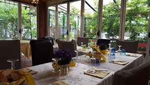 A dining area with tables set for a meal, featuring yellow napkins, clear glassware, and purple flowers. - Playa di Valverde - Campsite (Galliate)