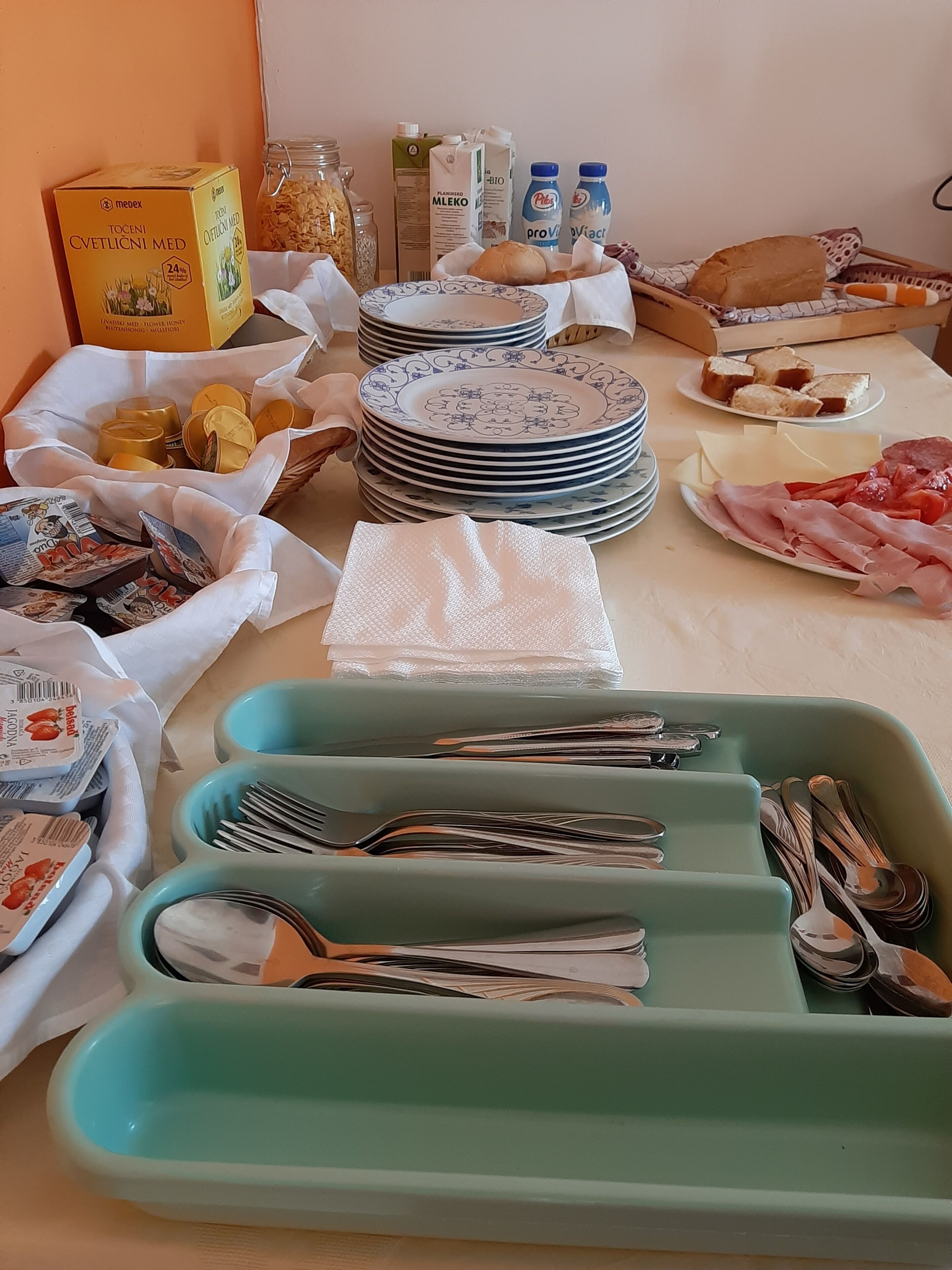 A table set with plates, bowls, utensils, and various food items.