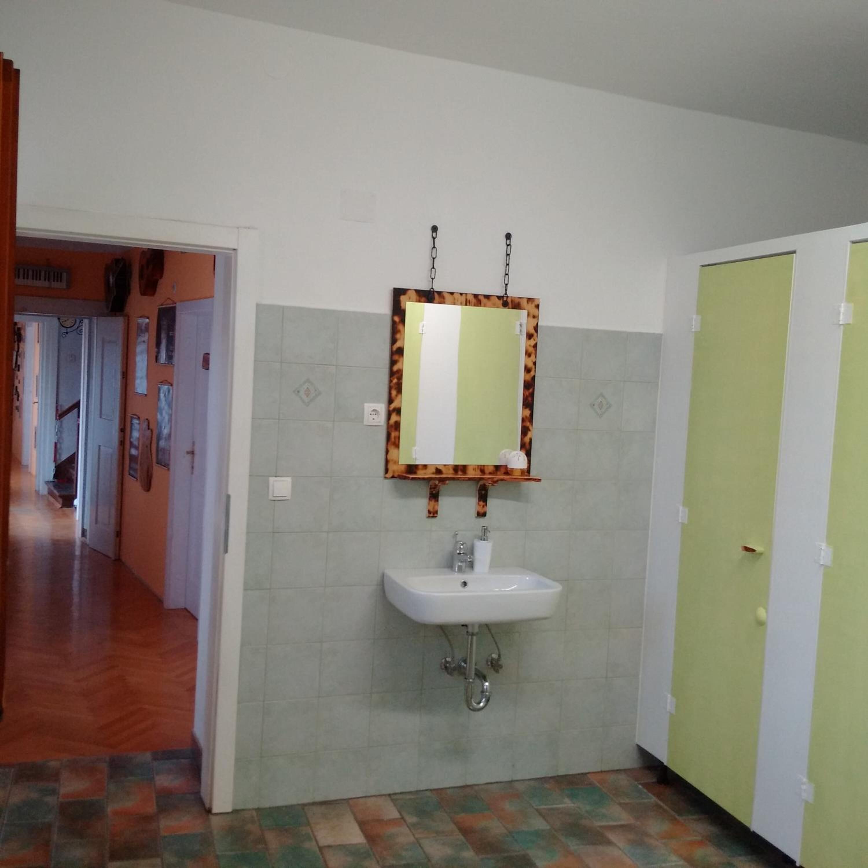 Un baño con lavamanos, espejo y paredes con azulejos.