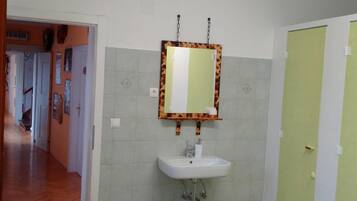 Un baño con lavamanos, espejo y paredes con azulejos.
