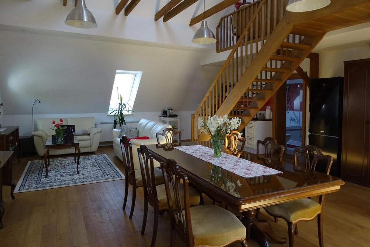 Ein geräumiges Loft mit Essbereich, einer Holztreppe und einer Küche.