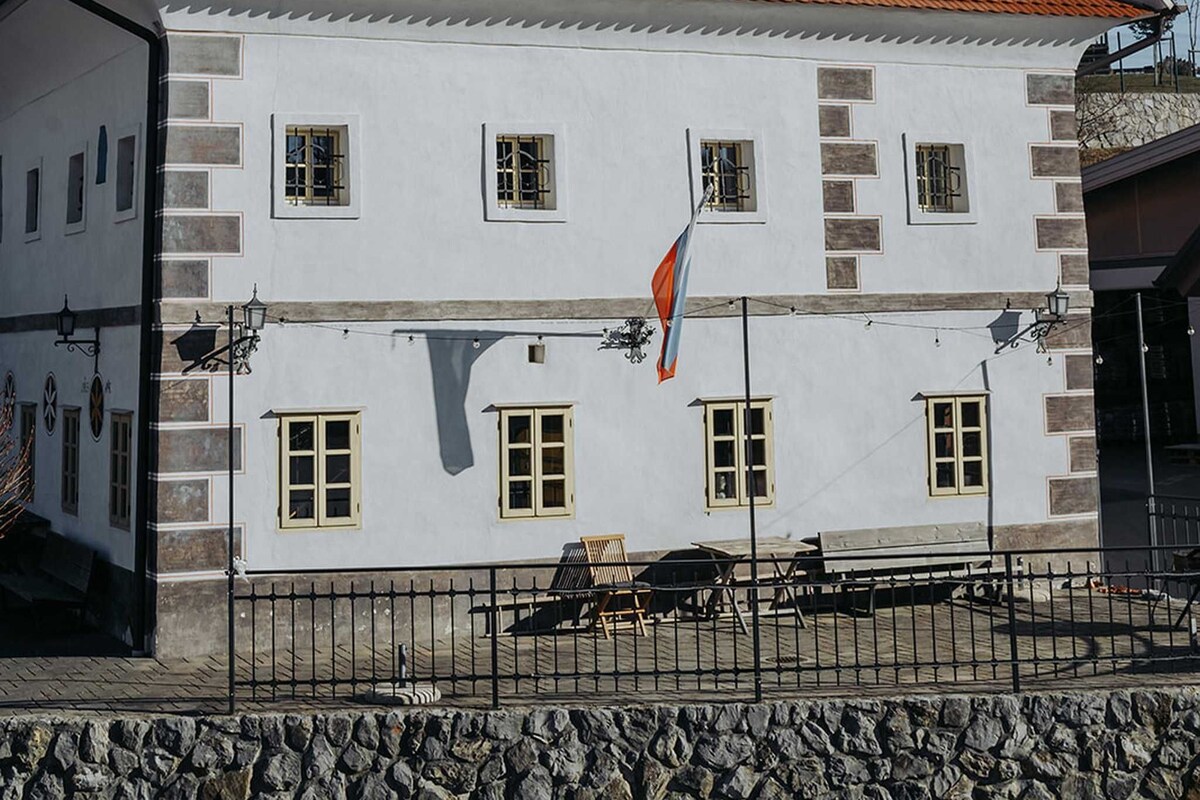 Ein weißes Gebäude mit rotem Ziegeldach, zahlreichen Fenstern und einer Flagge.