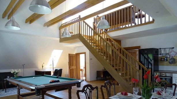 A spacious living room with a pool table, a dining area with a round table, and a staircase leading to an upper level. - Apartments Mozinetova hisa (Dobrova-Polhov Gradec)