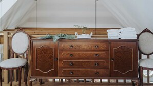 A wooden dresser with drawers and a plant on top, flanked by two upholstered chairs. - Apartments Mozinetova hisa (Dobrova-Polhov Gradec)